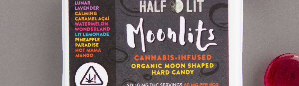 Rectangular box of Half Lit Moonlits Hard Candy with round, multicolored suckers placed around it.
