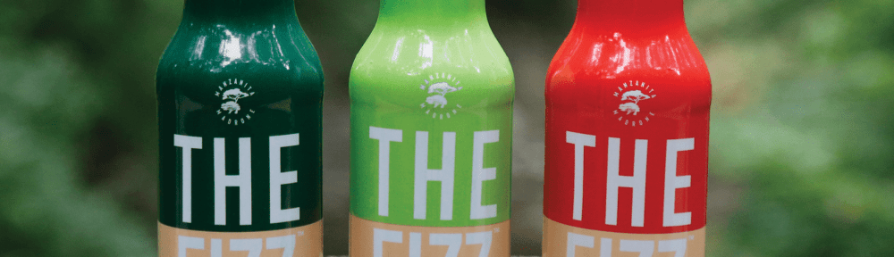 Three bottles on a ledge. Each on a different kind of a product called The Fizz, a cannabis infused beverage. Ginger Root, Lemon-Lime and Natural Cola flavor